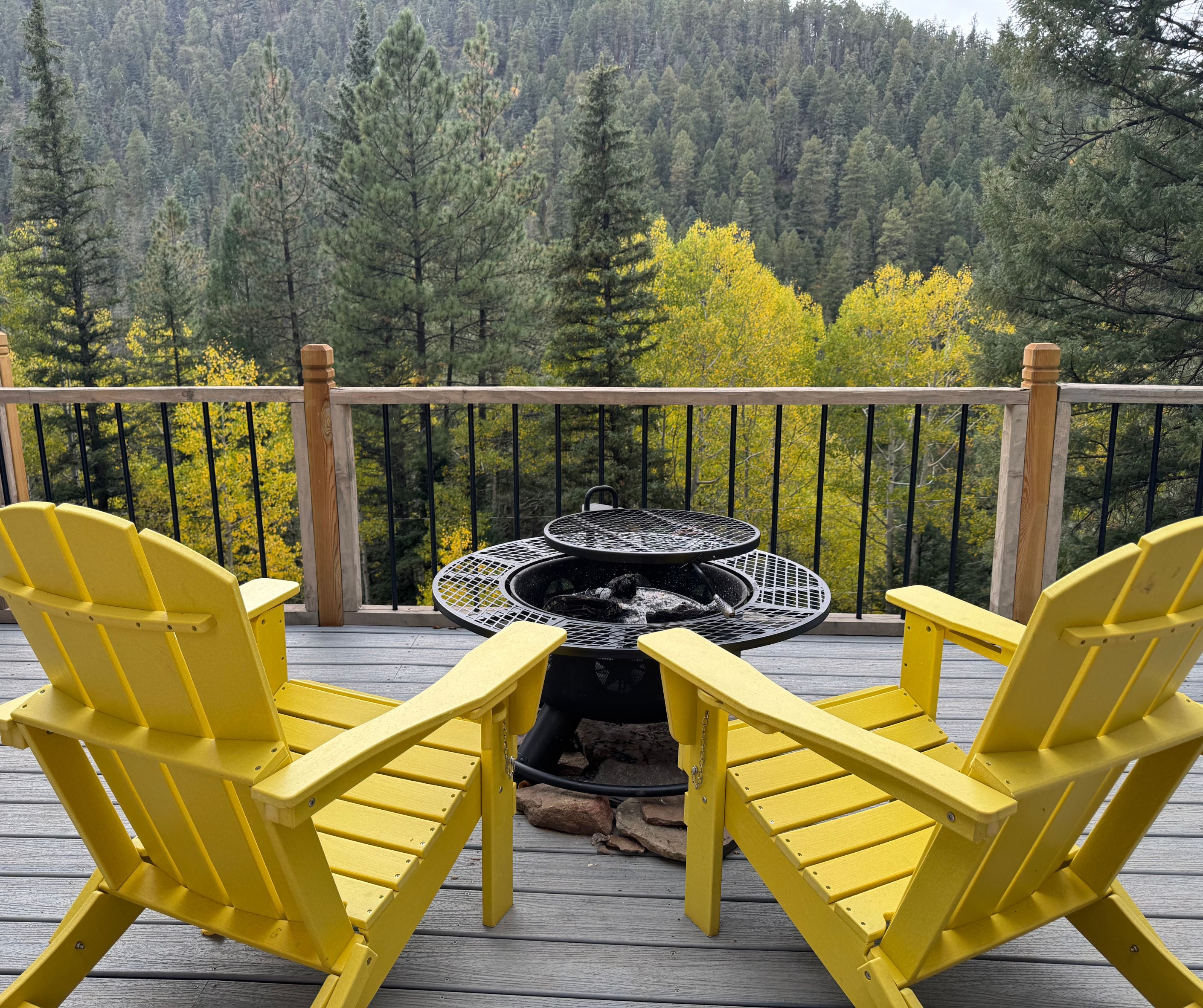 Two yellow chairs on a cabin deck overlooking the forest in Pecos Canyon